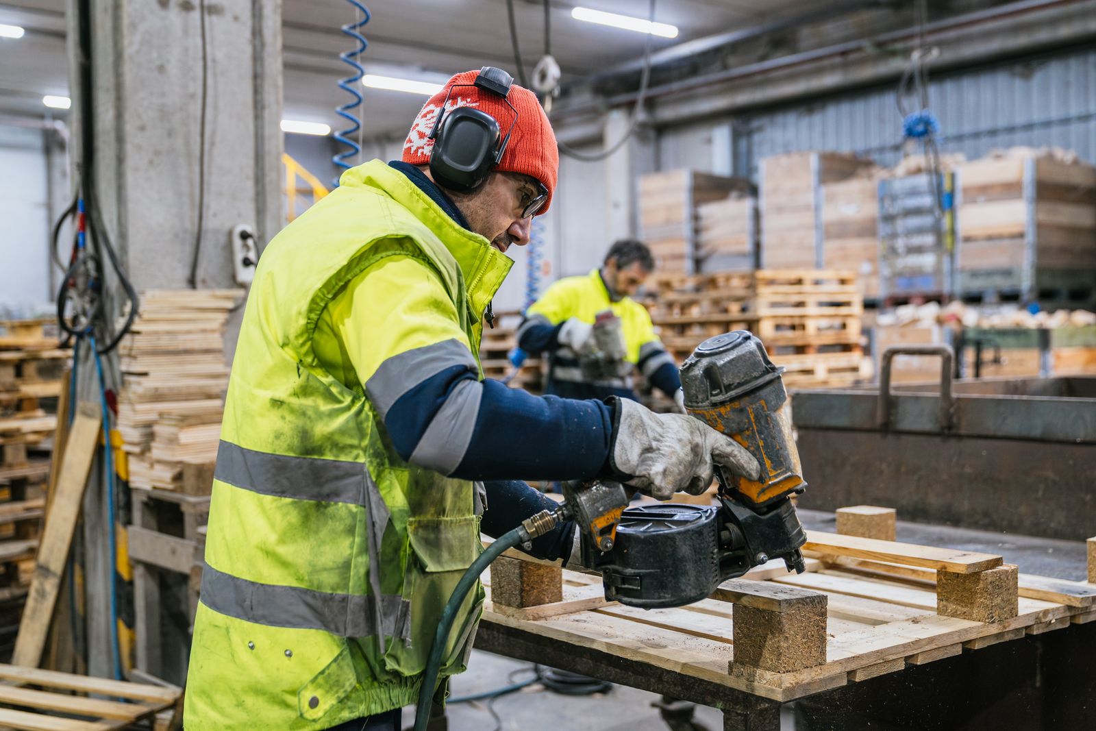 Mitarbeiter mit Gehörschutz baut Holzpaletten